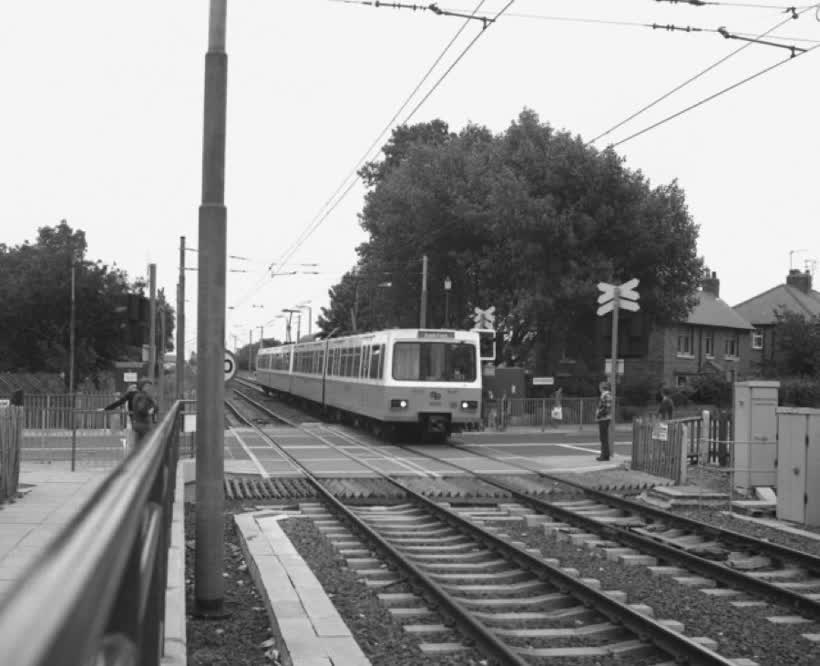 Fawdon station on the Tyne and Wear Metro. The view south east from Platform 1 across the ungated Fawdon Lane level crossing to an approaching train leaving Platform 2 bound for Bank Foot station (the terminus at this time)., close to the Aldi on Edgefield Avenue, Newcastle upon Tyne