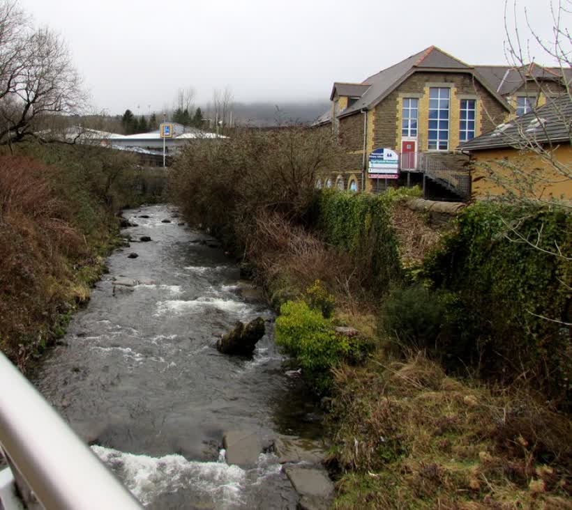 Upstream along the Llynfi, Maesteg. Viewed from a footbridge at the western end of Plasnewydd Street. The Llynfi is a tributary of the River Ogmore (Afon Ogwr in Welsh). Plasnewydd Primary School is on the right. An Aldi supermarket is in the distance., close to the Aldi on Llynfi Road, Maesteg